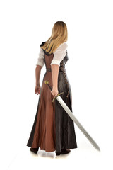 full length portrait of girl wearing brown  fantasy costume, holding a sword. standing pose on...