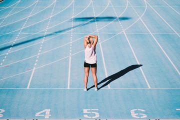 Caucasian young adult stretching arms before on running track