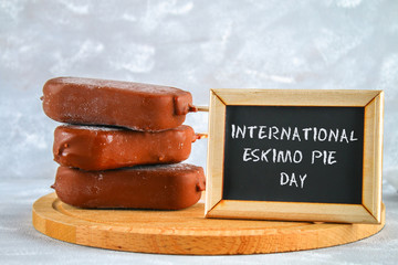 Ice cream eskimo pie on a stick with text on a gray background. Concept for the holiday International Eskimo pie day.