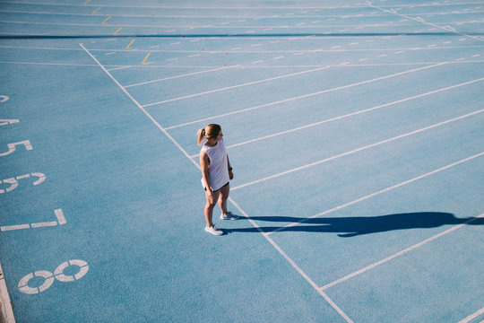 Young female athlete on blue running track