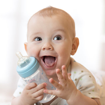 Sweet little baby holding plastic bottle