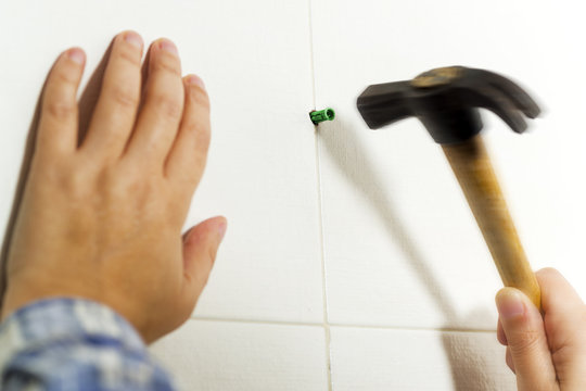 electrician woman placing rawlplug with hammer