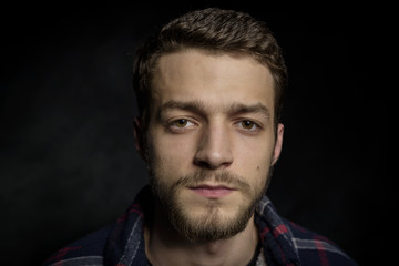 Portrait of a young man with a beard on a dark background.