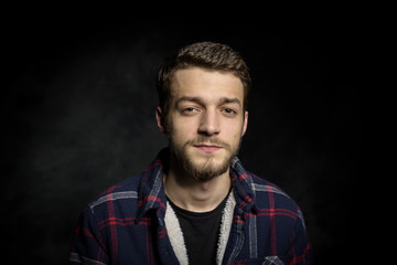 Portrait of a young man with a beard on a dark background.