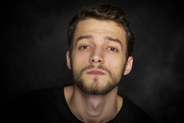 Fototapeta premium Portrait of a young man with a beard on a dark background.