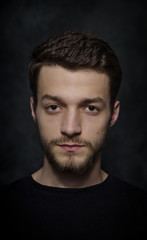 Fototapeta premium Portret młodego mężczyzny z brodą na ciemnym tle.