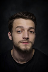 Naklejka premium Portrait of a young man with a beard on a dark background.