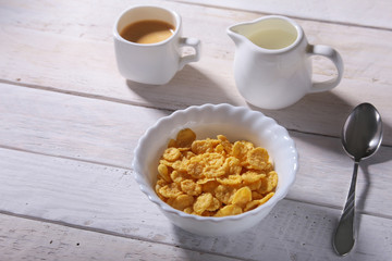 Corn Flakes cereal in a bowl, glass with milk and cap with espresso coffee. Morning breakfast.