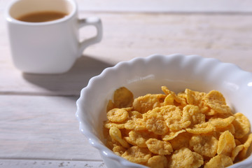 Corn Flakes cereal in a bowl, glass with milk and cap with espresso coffee. Morning breakfast.