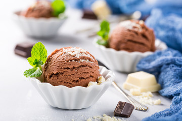Chocolate ice cream scoop in white bowl with chopped white chocolate and mint decoration. Summer food concept.