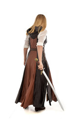 full length portrait of girl wearing brown  fantasy costume, holding a sword. standing pose on...