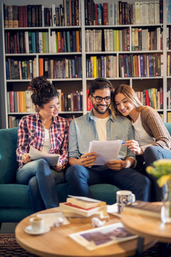 Adorable cute stylish high school student group sitting on the sofa and learning together in the library.