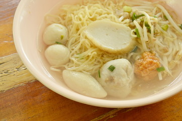 Chinese egg noodles topping fish dumpling and shrimp ball in clear soup on bowl