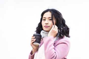Asian woman holding paper cup of hot drink