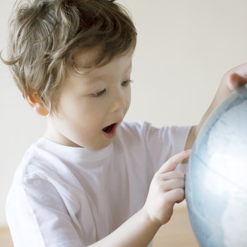 Close-up of boy looking at globe while sitting at home