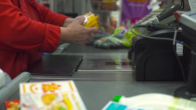 Close up check out counter. Senior female hands working on cash register in the supermarket