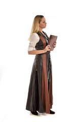  full length portrait of girl wearing brown  fantasy costume, holding a book. standing pose on white studio background. 