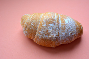 appetizing freshly baked croissant with powdered sugar close-up isolated