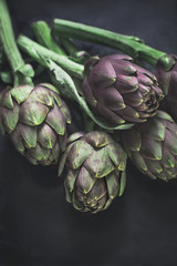 Fresh textured artichokes on a dark background. Ingredients of southern Italian cuisine. Vertical...