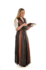  full length portrait of girl wearing brown  fantasy costume, holding a book. standing pose on white studio background. 