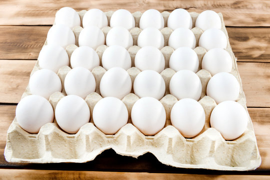 Eggs in tray of carton on wooden background.