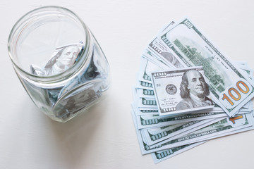 glass jar with donations and dollars on white background