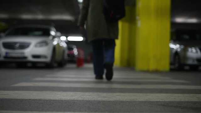 Pregnant caucasian woman walking on pedestrian zebra crossing in underground public garage