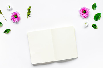Flower petals and white notebook on table background top view mo