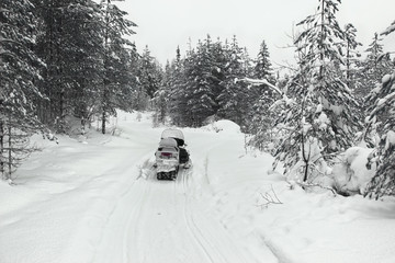 Winter snowy lanscape with road end athletes on a snowmobile