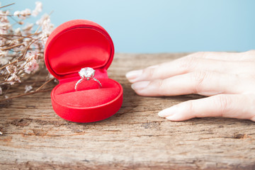 Diamond ring in red box with woman hand on wooden table, Engagement ring, Valentine's Day