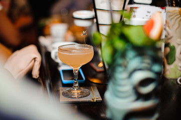 Elegant cocktail glass filled with alcoholic drink on the bar counter