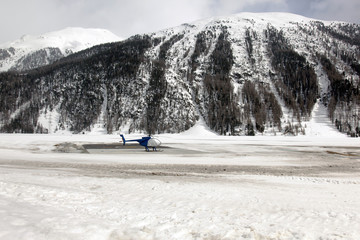A helicopter in the beautiful scenics of snow covered landscape and mountains in the alps...
