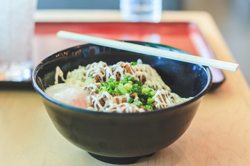 Rice with Teriyaki chicken rice and poached egg (Onsen egg), mayonnaise and coriander on top in the bowl and chopstick , Japanese food in the resturant 