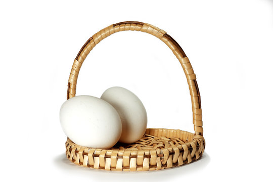 Wicker basket with two white Easter eggs isolated on a white background