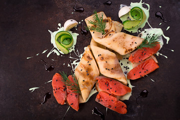 Pancakes with salmon and sauce on a black background. Horizontal top view