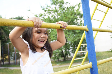 Fototapeta premium Playful latin little girl climbing on the playground. 