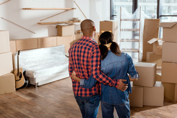 Fototapeta na wymiar back view of african american couple looking at new home with cardboard boxes