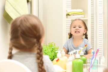 Cute little girl brushing teeth in bathroom