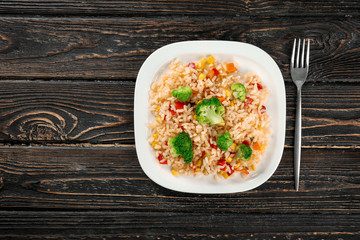 Plate with rice pilaf and broccoli on wooden table