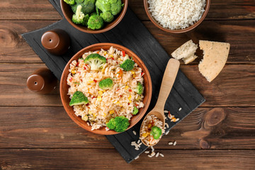 Delicious rice pilaf with broccoli in bowl on wooden table