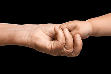 Hands of elderly man and baby on dark background