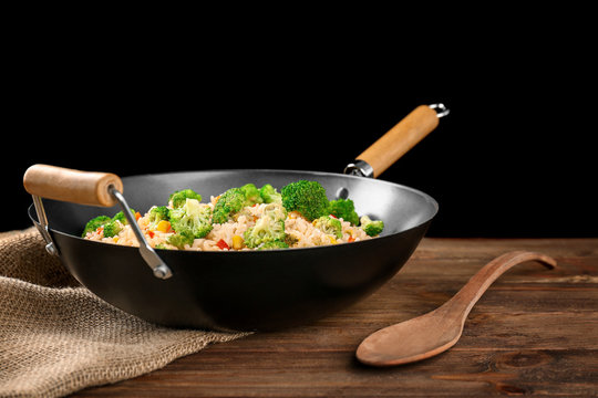 Delicious rice pilaf with broccoli in wok on wooden table