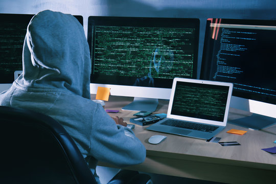 Man wearing hoodie hacking server in dark room