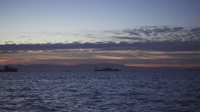 Evening sea after sunset and on the horizon ships in the roadstead