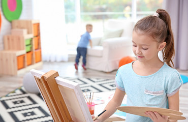 Little girl painting on canvas at home