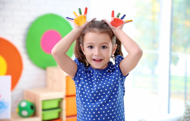 Little girl with painted palms indoors
