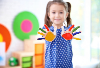 Little girl with painted palms indoors