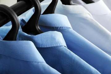 Obraz premium Clean shirts hanging on rack in laundry, closeup