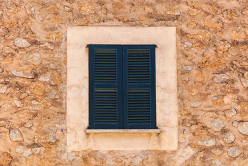 Fototapeta na wymiar Old rustic stone house wall with closed window shutters, detail close-up, mediterranean background texture.wooden shutters