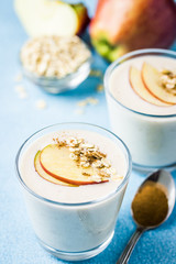 Healthy apple crisp oat smoothie in glasses on light blue background. Selective focus, space for text. 
